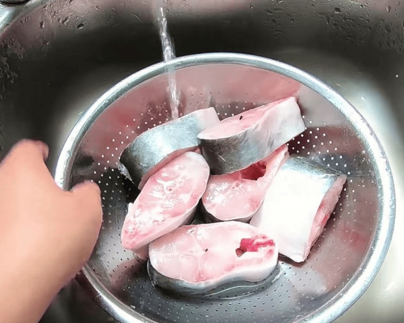 Làm sạch cá basa cắt khúc, rửa dưới vòi nước để ráo