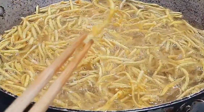Chiên khoai môn bào sợi trên chảo dầu