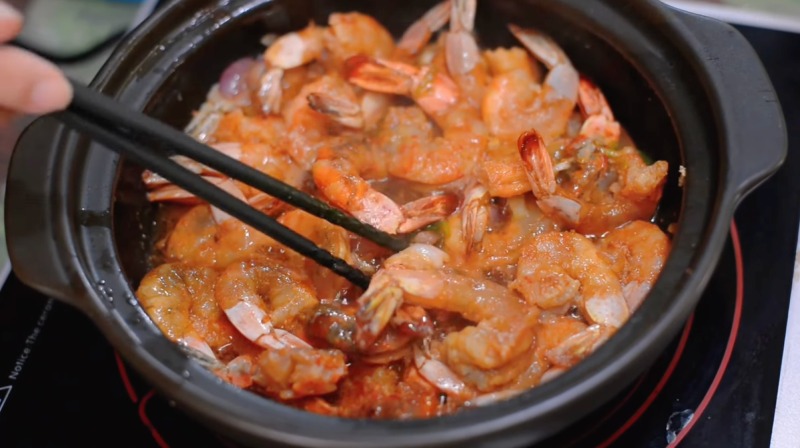 Đảo tôm trong nồi khi kho tộ để thấm đều gia vị