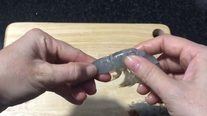 Dùng hai ngón tay giữ lấy đuôi và tách vỏ tôm