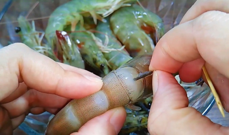 Dùng tay kéo hết phần chỉ ra khỏi thân tôm