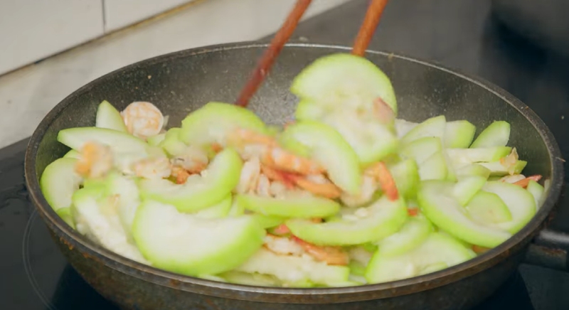 Cho bầu xào với tôm và đảo đều