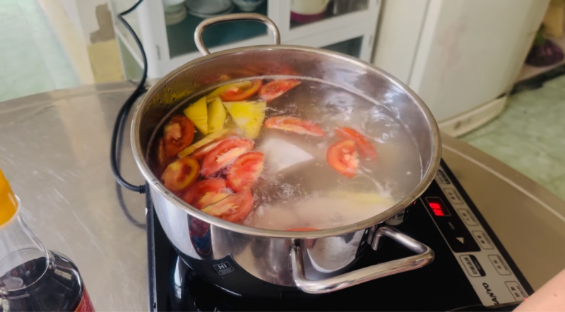 Nấu nước dùng trong cho bún cá chim với cà chua và dứa
