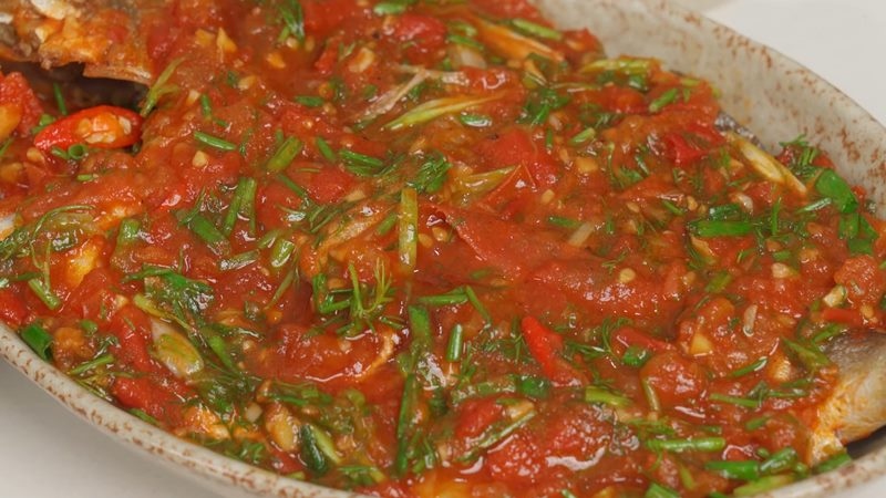 Cá chim sốt cà chua hoàn thành với hành lá và thì là