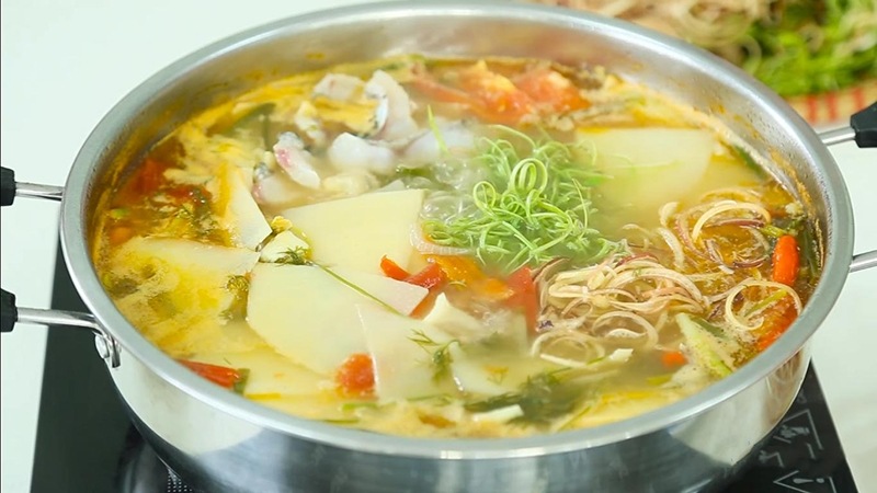 Nồi nước lẩu cá lóc măng chua đang sôi với măng và cà chua