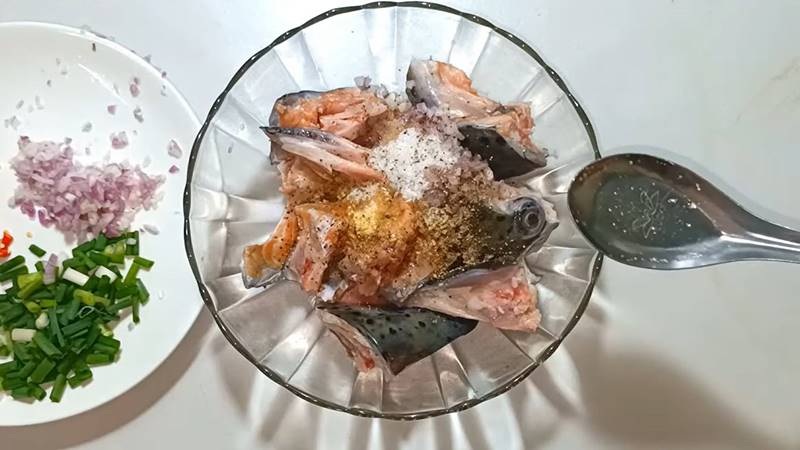 Sơ chế xương cá hồi ướp gia vị chuẩn bị nấu canh chua