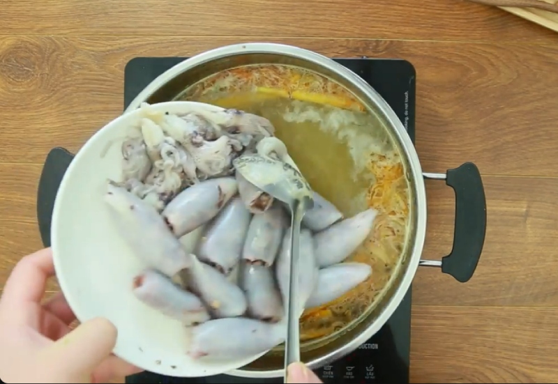 Cho mực vào nồi nước lẩu đang sôi