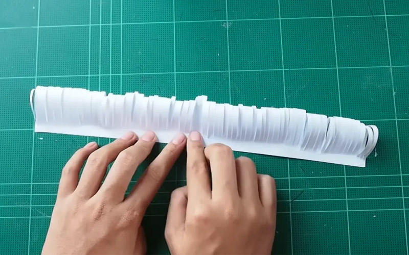 Cắt tua rua tờ giấy A4 đã cắt và cố định hai đầu lại