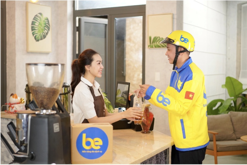 Tài xế BeFood trong đồng phục vàng nhận đồ uống từ quán