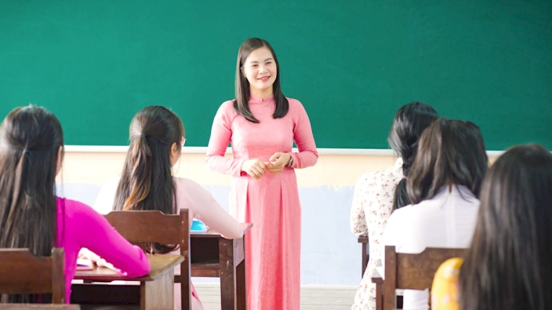 Cô giáo áo dài hồng đứng giảng trước lớp học