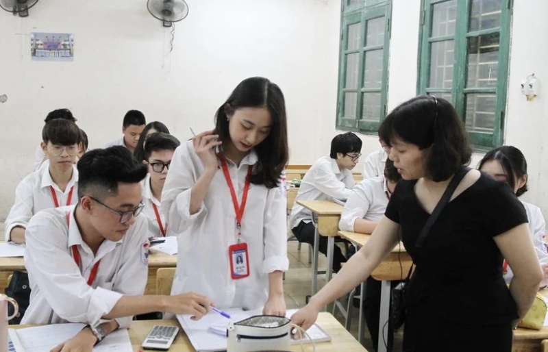 Cô giáo hướng dẫn học sinh làm thủ tục dự thi