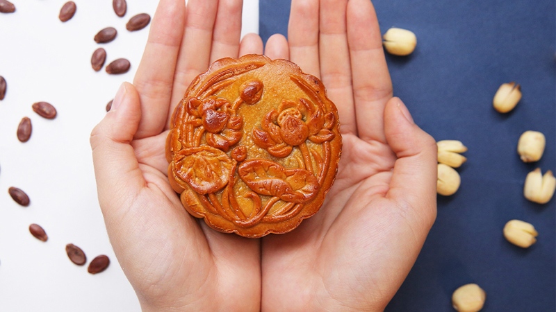 Bánh Trung Thu nướng được cầm trên tay, vỏ bánh vàng ươm