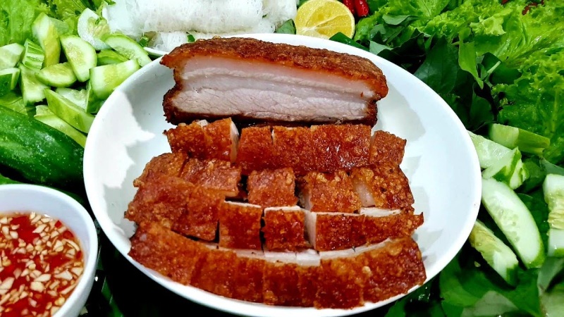 Thịt heo quay giòn rụm xếp trên đĩa cùng rau sống