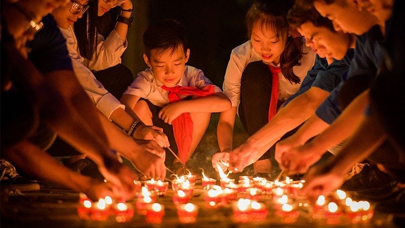 mọi người ngồi xung quanh nhau và thắp ngọn nến