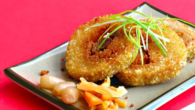 Đĩa bánh tét chiên giòn vàng ăn kèm dưa món và hành muối