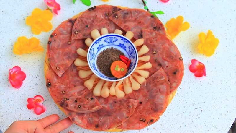 Đĩa chả bong bóng heo cắt lát bày cùng chén tiêu chanh.