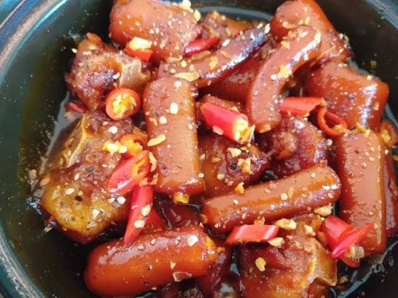 Đuôi heo kho tiêu trang trí ớt và rau mùi trong nồi