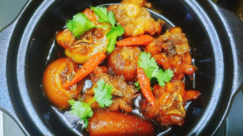 Đuôi heo kho tiêu trang trí ớt và rau mùi trong nồi