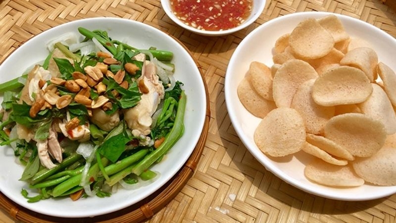 Đĩa gỏi gà trộn rau nhút rắc đậu phộng rang, dùng kèm bánh phồng tôm và nước chấm chua ngọt.