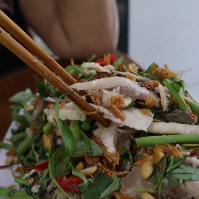 Gà xé, rau nhút, rau răm, hành phi, đậu phộng và nước trộn được trộn đều tay