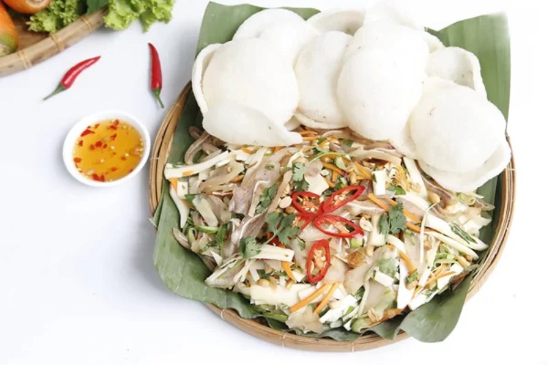 Gỏi tai heo hành tây bày trên mẹt kèm bánh phồng tôm và nước mắm tỏi ớt