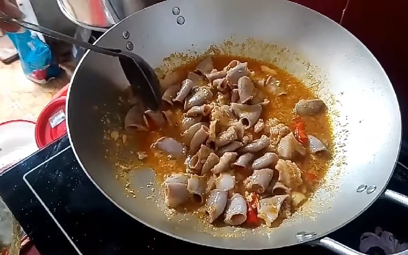 Lòng heo đang được xào sơ trong chảo lớn.