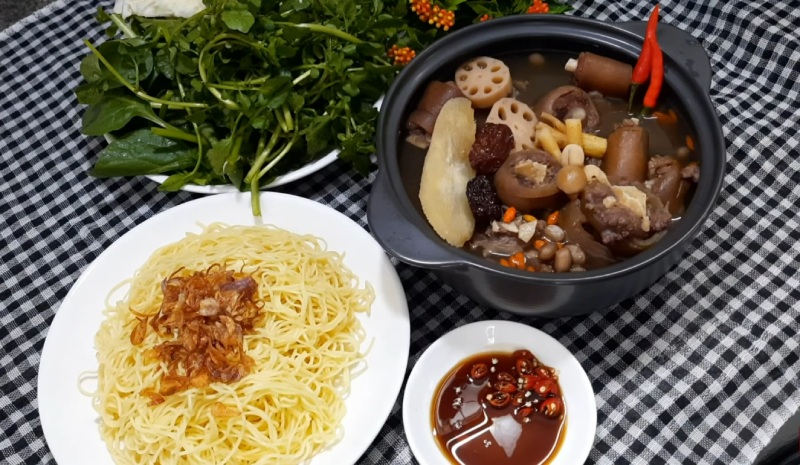 Nồi đuôi bò hầm thuốc bắc nóng hổi ăn kèm mì trứng, rau sống và nước chấm