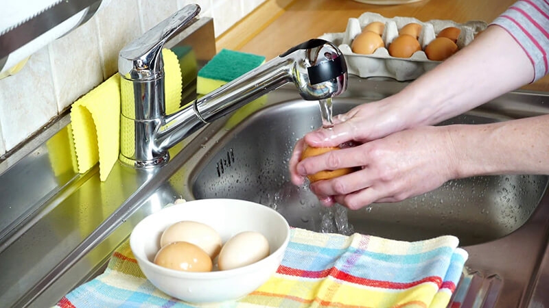 Rửa sạch trứng gà dưới vòi nước