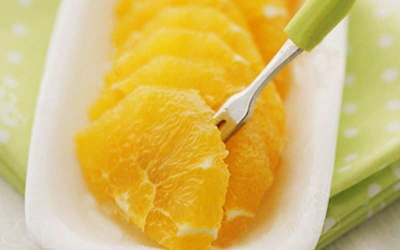 Miếng cam đã bóc vỏ xếp trên đĩa trắng