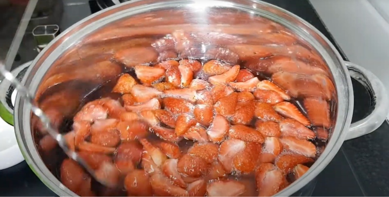 Dâu tây cắt đôi đang đun trong nồi để nấu mứt pha nước