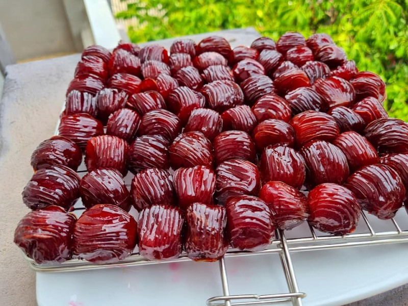 Mứt táo khía màu đỏ bóng phơi trên vỉ inox