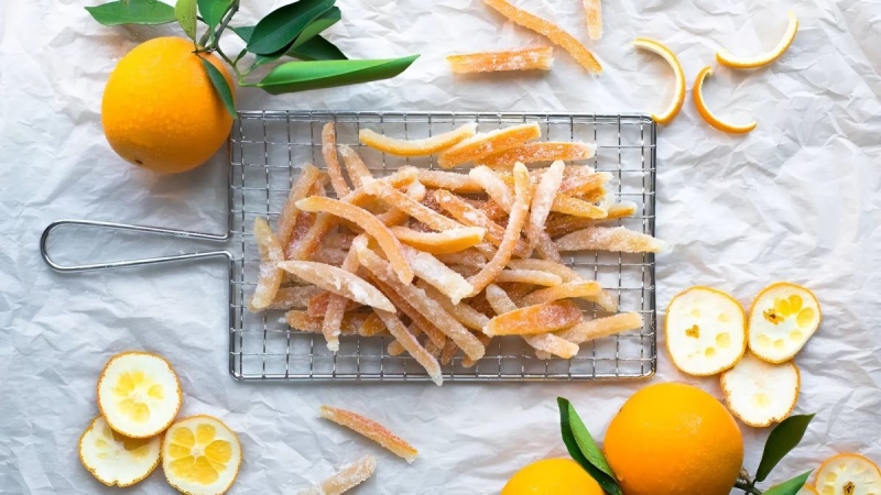Mứt vỏ cam sấy khô bày trên khay cùng cam tươi