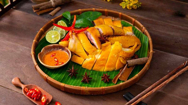 Gà ủ muối chặt lát được chặt miếng bày trên mẹt lót lá chuối, kèm nước chấm đậm vị 