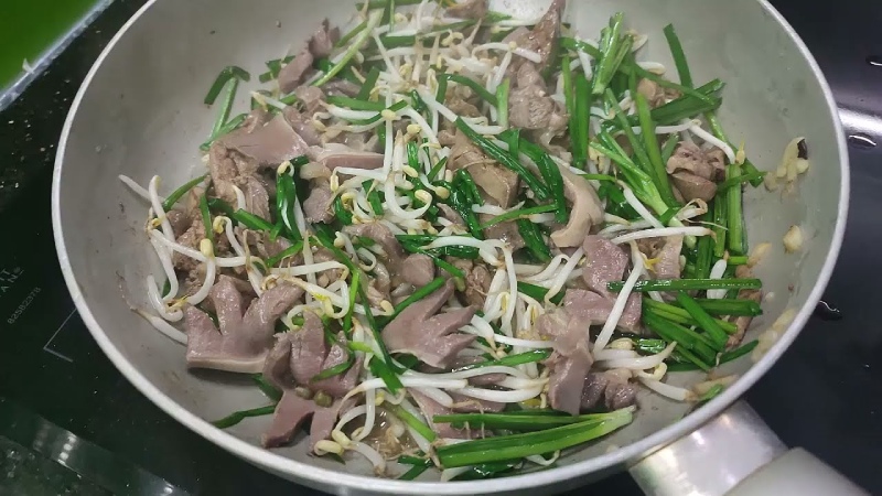 Xào tim heo với giá đỗ và hành lá trong chảo nóng đều tay