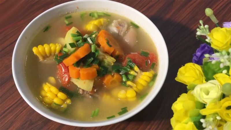 Canh bắp hầm giò heo với cà rốt, cà chua, hành lá.