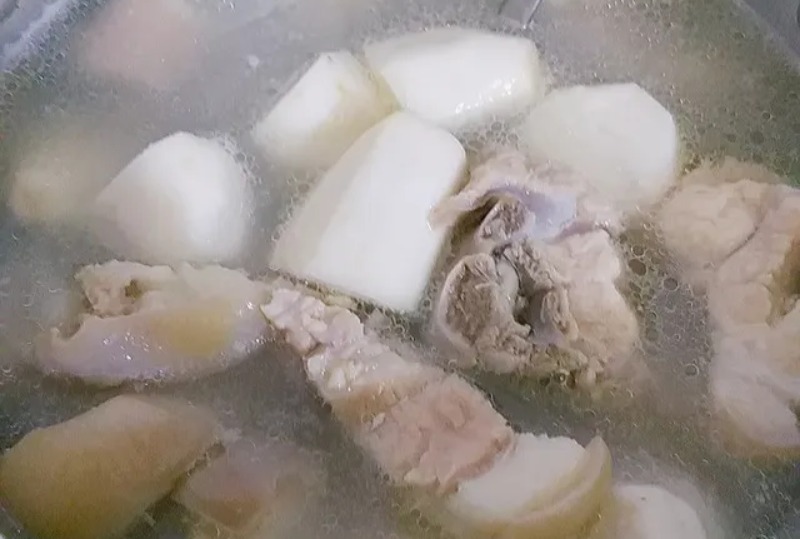 Đuôi heo và khoai môn đang được ninh mềm trong nước dùng trong