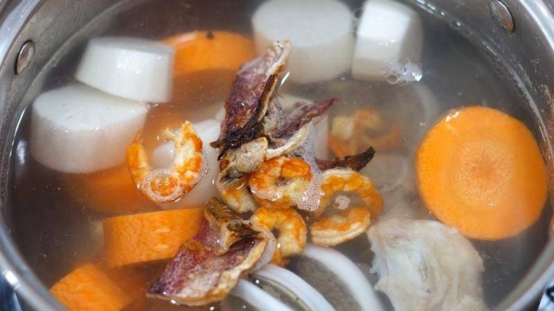 Nồi nước dùng ninh củ cải, cà rốt, tôm khô và mực khô