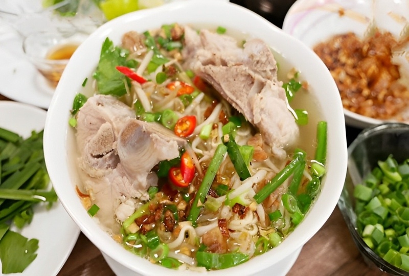 Tô hủ tiếu xương heo nóng hổi với hành, ớt và rau thơm