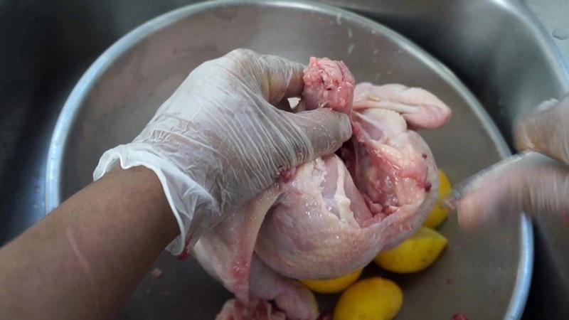 Làm sạch gà nguyên con bằng cách chà xát với muối và chanh (hoặc giấm) để khử mùi hôi