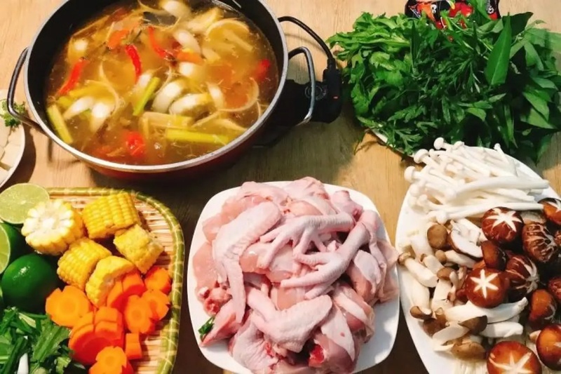 Mâm lẩu hoàn chỉnh với thịt gà, rau, nấm, bắp và nước lẩu đang sôi