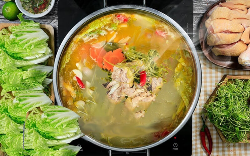 Nồi lẩu gà nước dừa đang sôi với thịt gà, rau, ớt và cà rốt