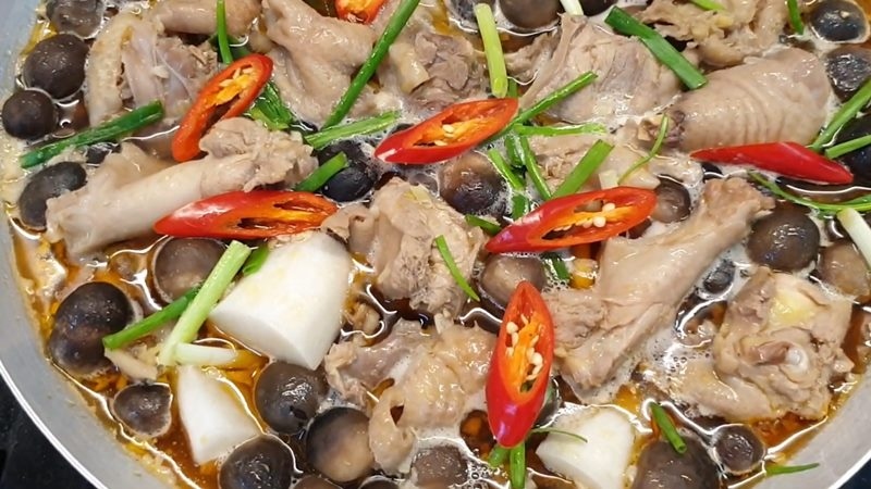 Món ăn đã hoàn tất, có gà, nấm, củ cải, hành lá và ớt đỏ tươi trang trí