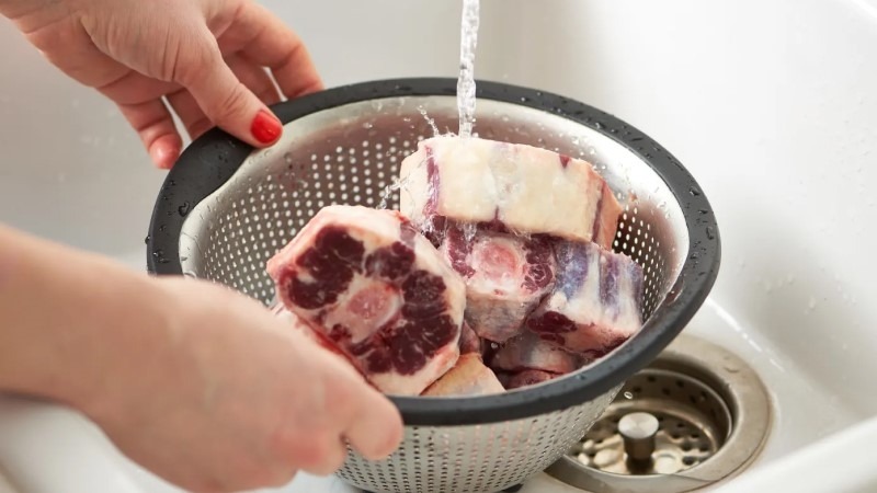 Sườn heo tươi đang được rửa sạch dưới vòi nước