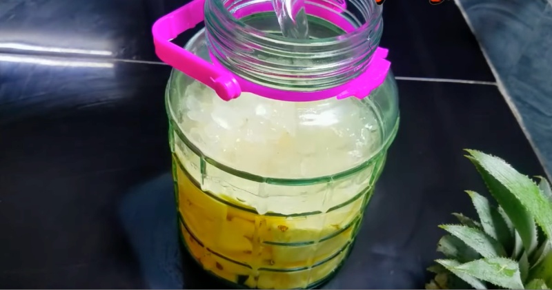 Đổ nước lọc vào hũ dứa để chuẩn bị ngâm trứng gà