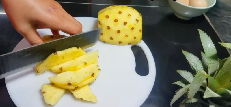 Cắt dứa thành lát mỏng trên thớt trắng để chuẩn bị ngâm