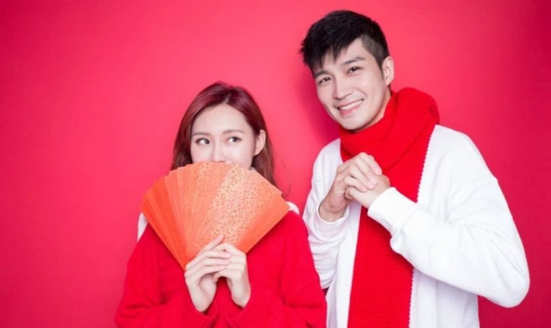 Cặp đôi tạo dáng Tết với phông nền đỏ