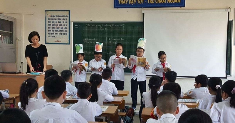 Hình ảnh học sinh đọc bài trước lớp trong giờ học cùng cô giáo