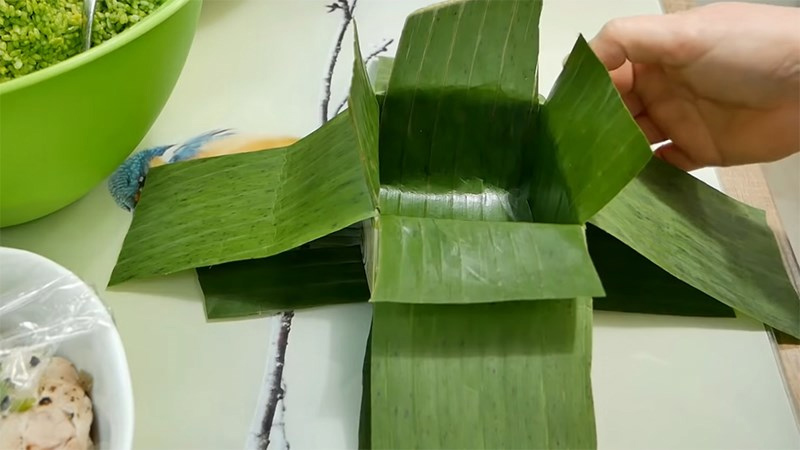 Đặt chéo hai miếng lá lớn còn lại vào giữa hộp và ngửa hai mặt lá đậm lên