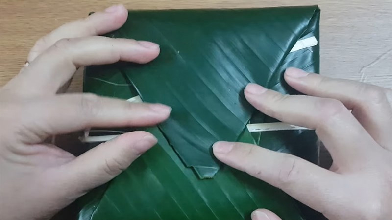 Gấp hai mép lá lại để hoàn thành chiếc bánh chưng của mình