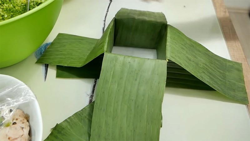 Gấp đôi miếng lá lớn lại và luồn qua một cạnh của hộp